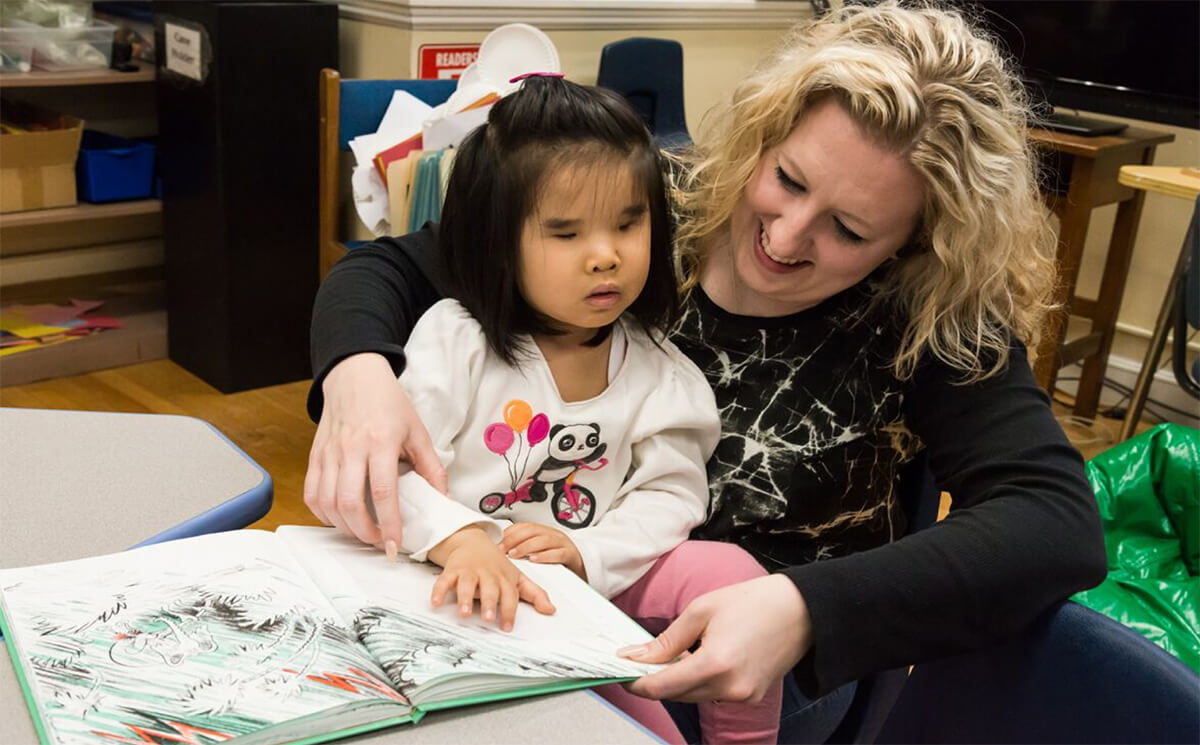 Blind child reading with educator