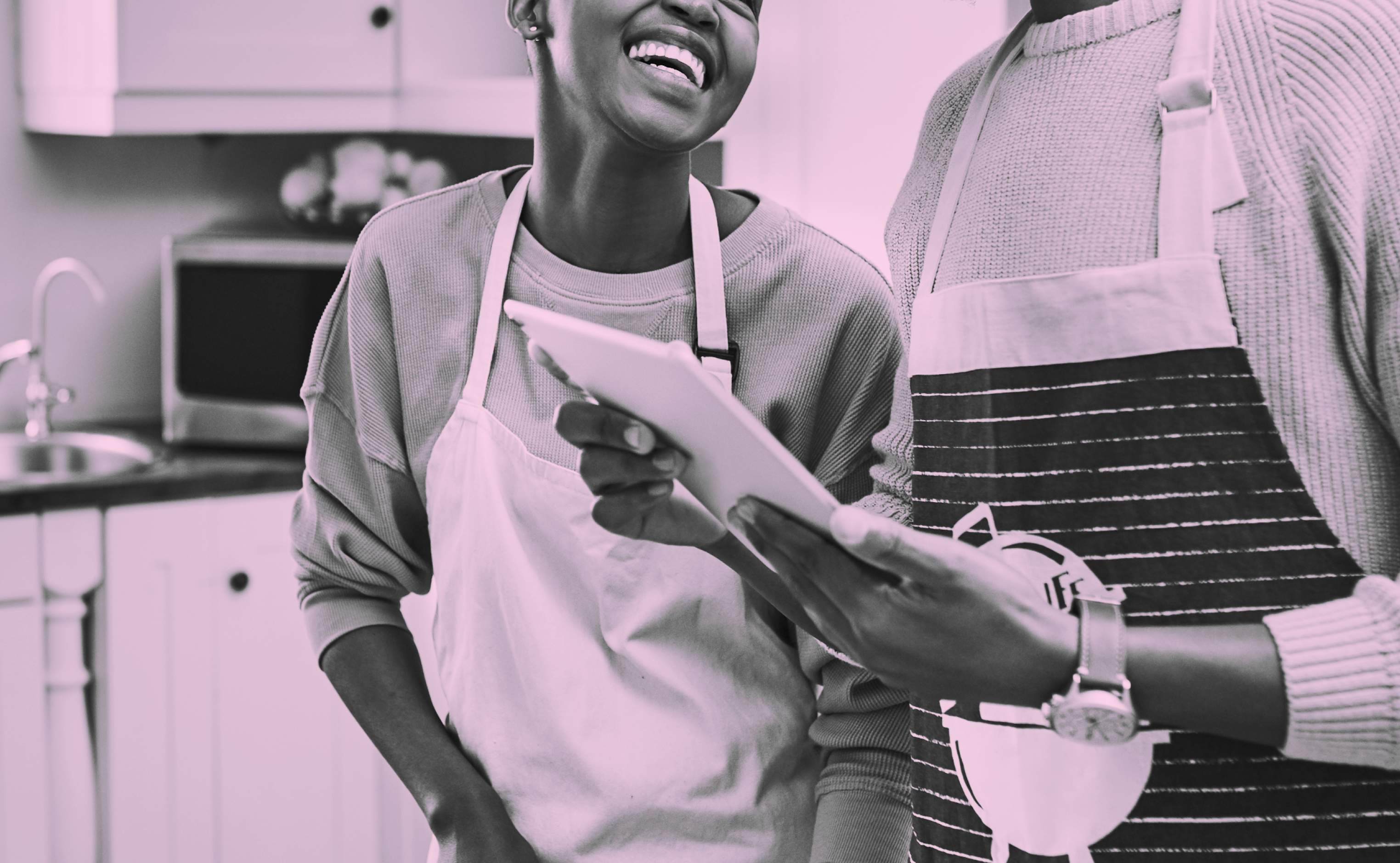 Two people in a kitchen cooking, the woman smiling up at the other individual. Pink overlay on the image
