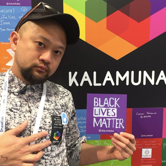 Ken holds up a colored sticker that reads "Black Lives Matter."