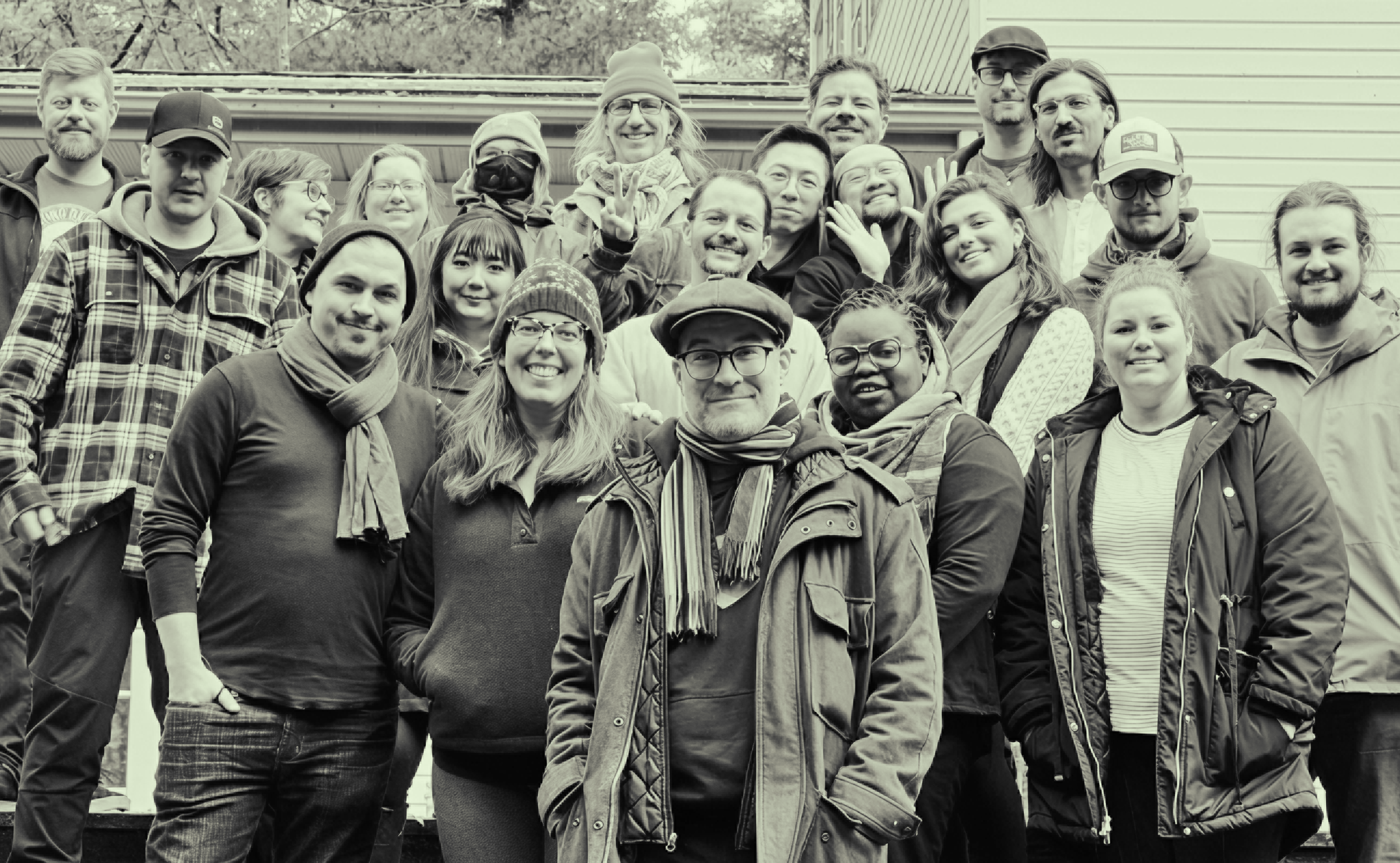 Kalamuna team picture with over 20 people in warm jackets with a green hue overlay. 