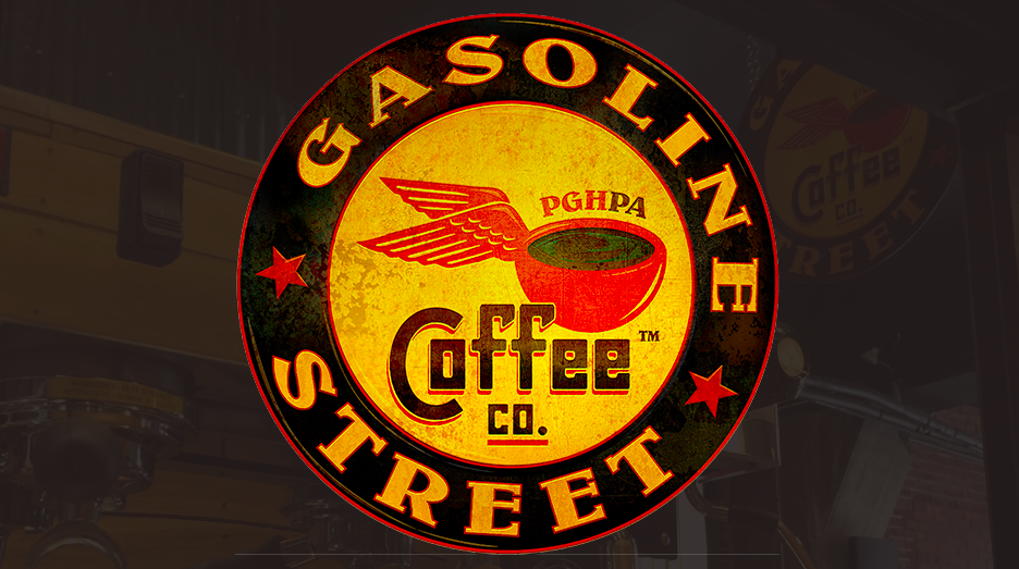 The logo of Gasoline Street Coffee Company. A circle, red, yellow, and black, with a coffee cup that has wings attached. 