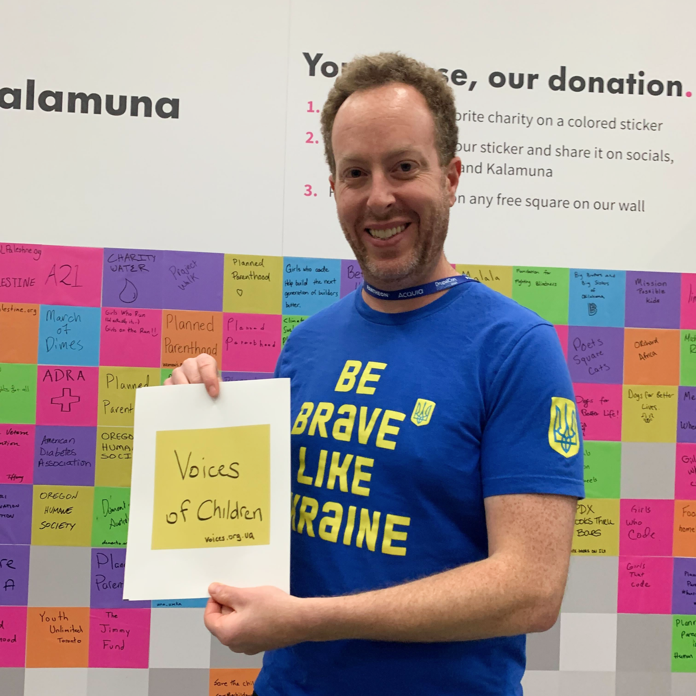 Avi Schwab holds a yellow square sticker with "Voices of the Children" written on it.
