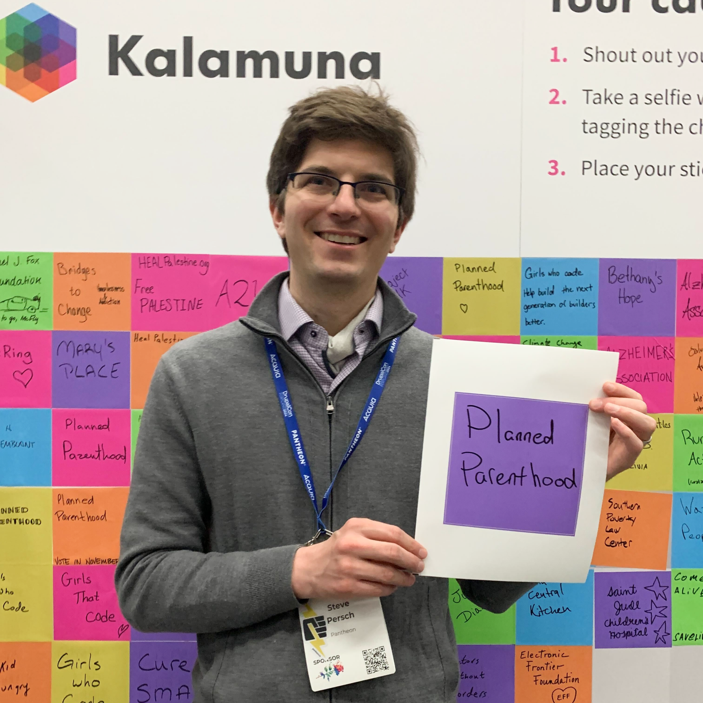 Steve Persch holds a purple square sticker with "Planned Parenthood" written on it.