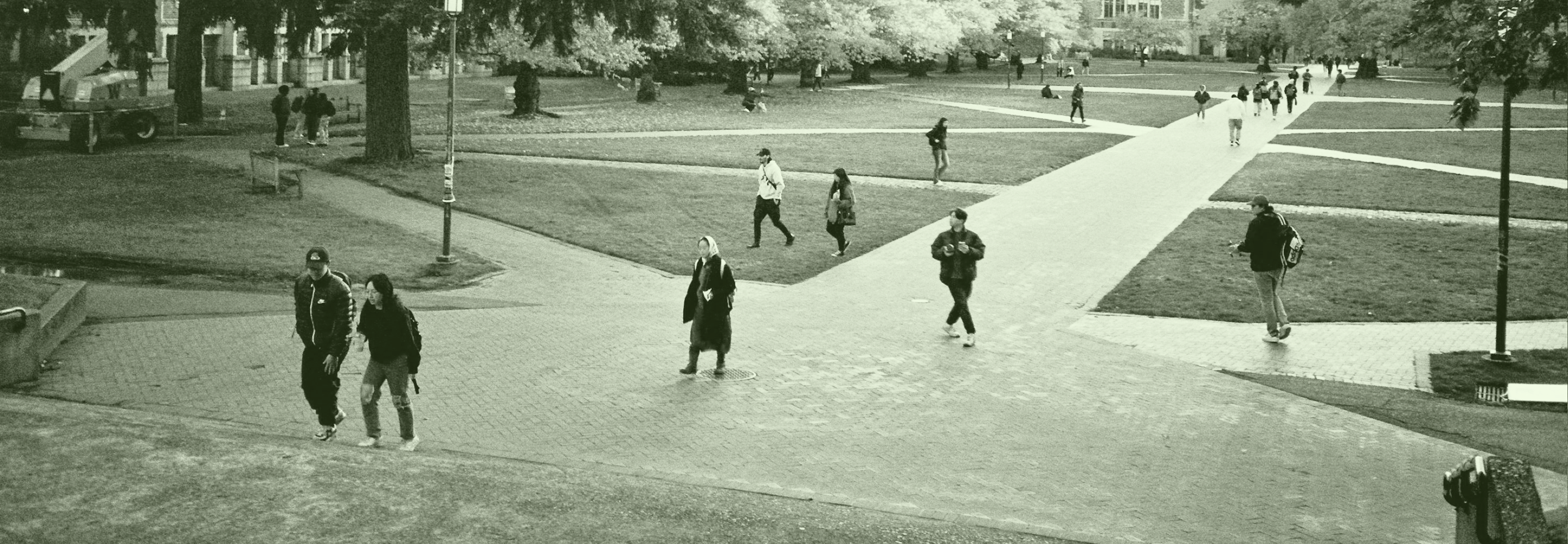 Photo of university students walking through an outdoor campus area with criss-crossing paths