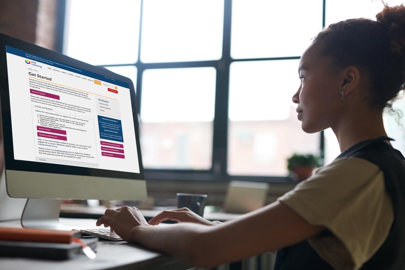 A young student logs into her computer to review VHS Learning's website