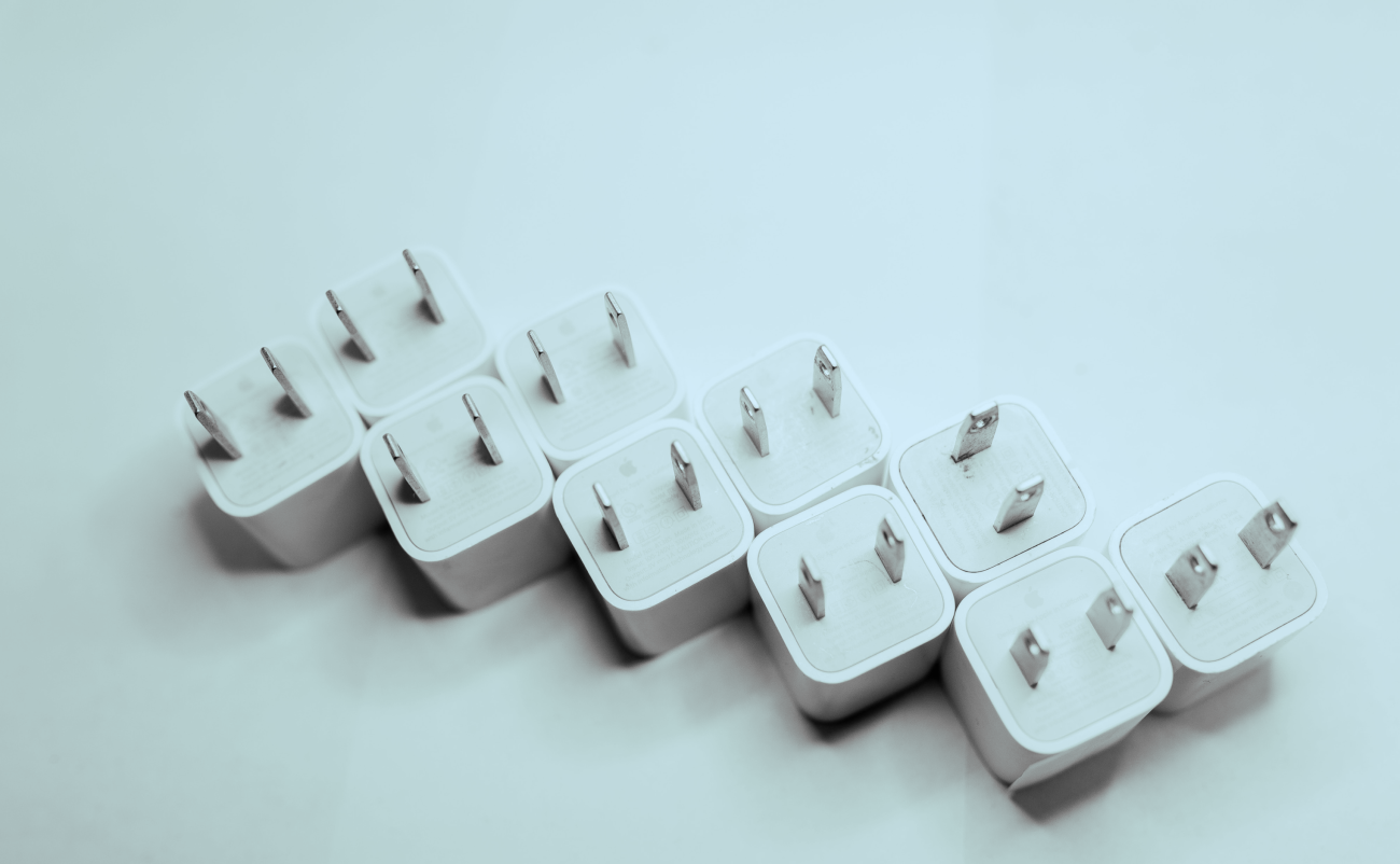 A row of 10 plugs to go into the wall laying next to each other. Blue overlay over the image, blank background. 