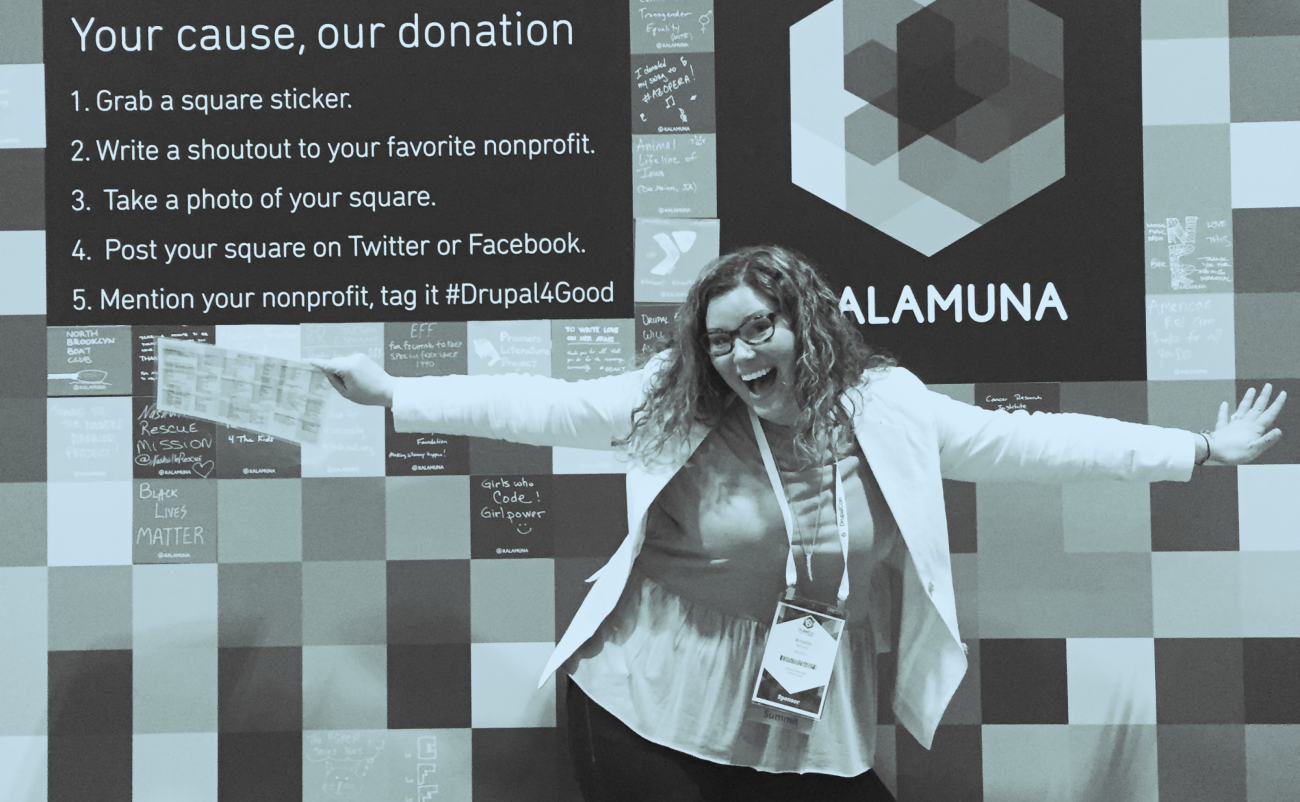 Kristin posing excitedly with arms open in front of Kalamuna's donation booth with a blue hue overlaying the image