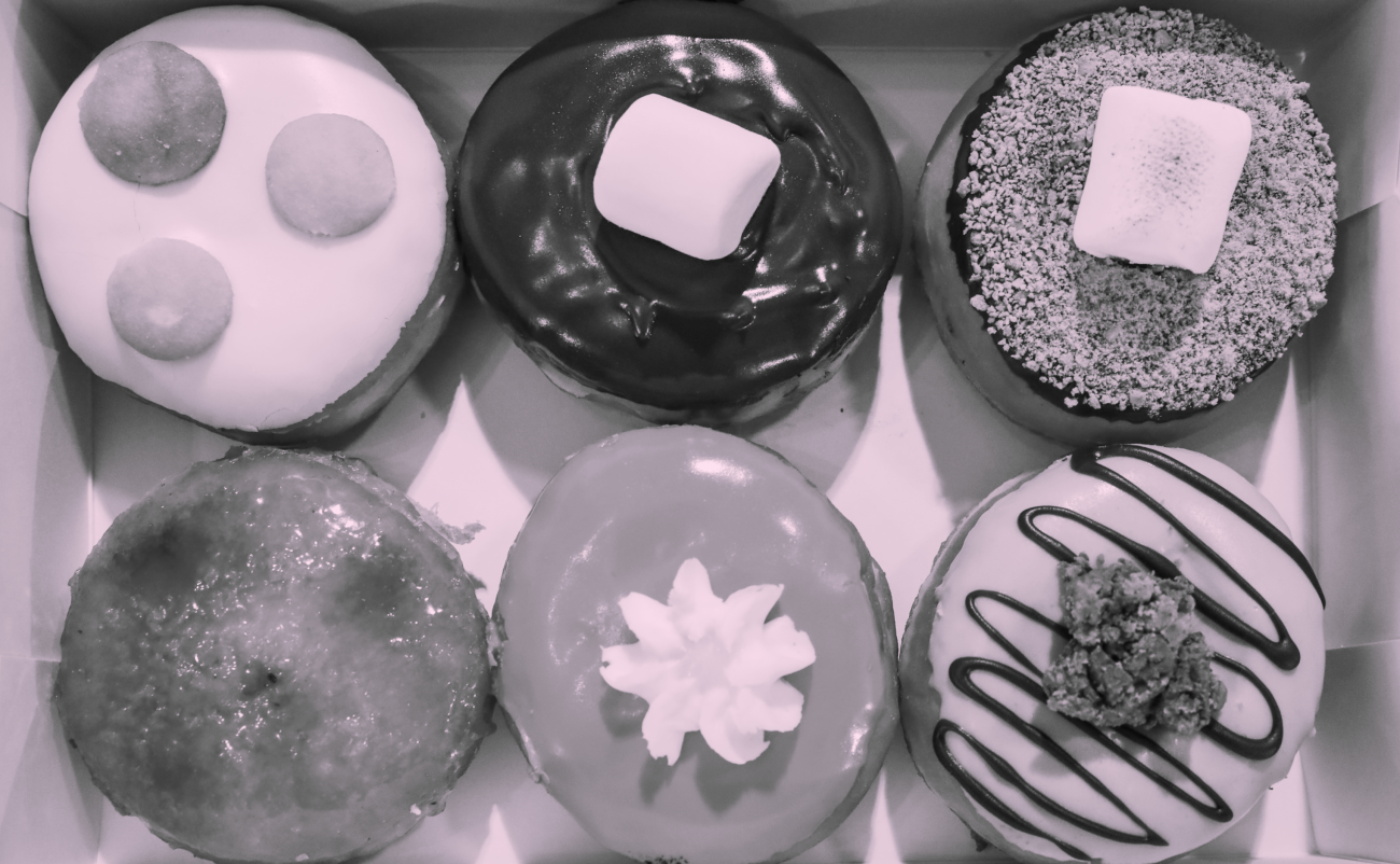 A flat lay view of 6 doughnuts with varying finishes, textures, and toppings.