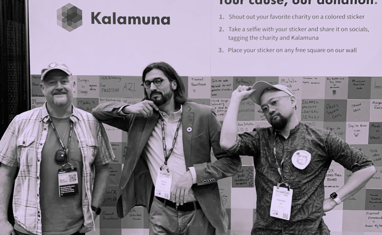 Bob, Andrew, and Ken stand in front of Kalamuna's booth wall. 