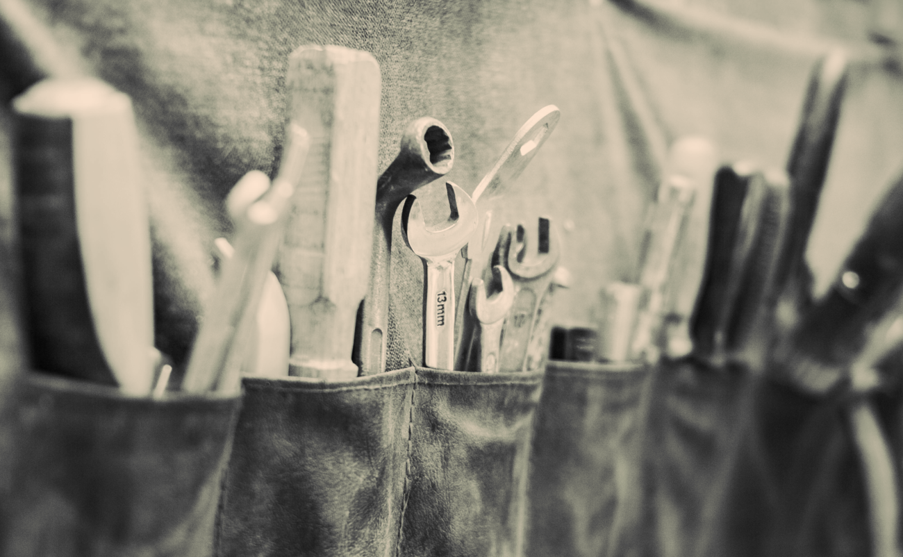 Toolbelt with multiple pockets holding tools including wrenches, hammers, and more.